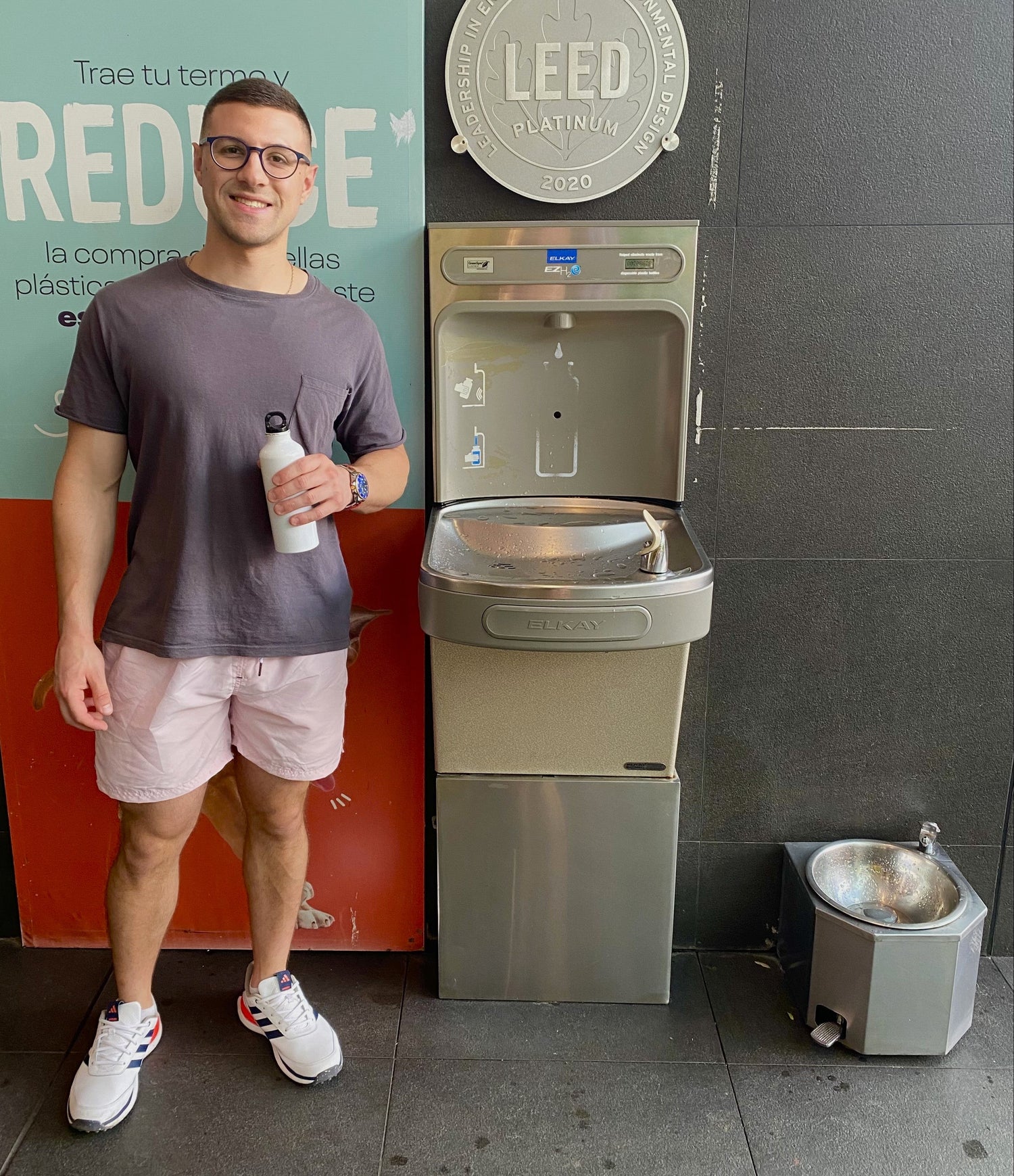 Person holding a bottle next to a water dispenser with a LEED sign in the background